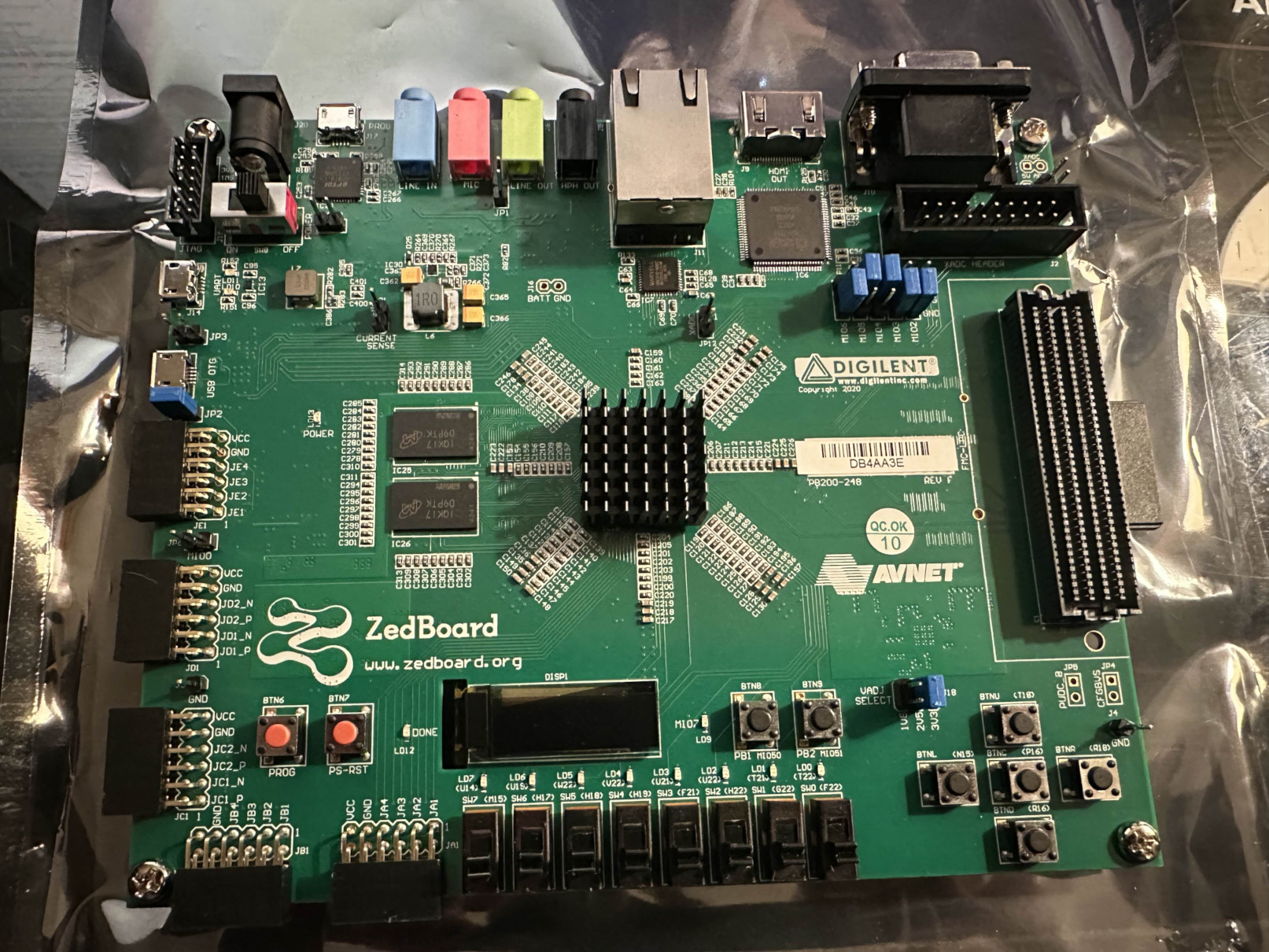 Picture of a ZedBoard development board, green PCB with connectors and buttons. Board is unplugged, sitting on top of its anti-static bag